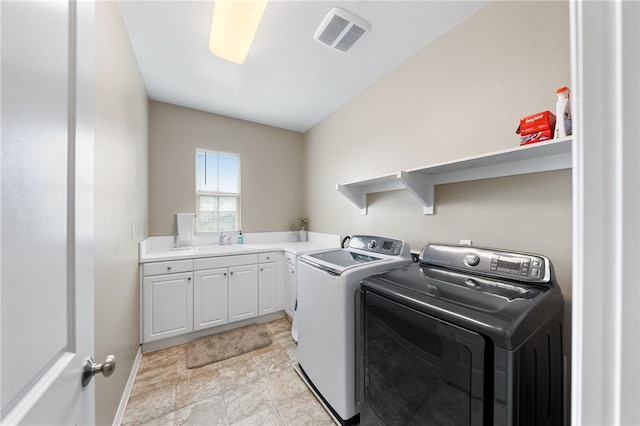 washroom with sink, washing machine and dryer, and cabinets