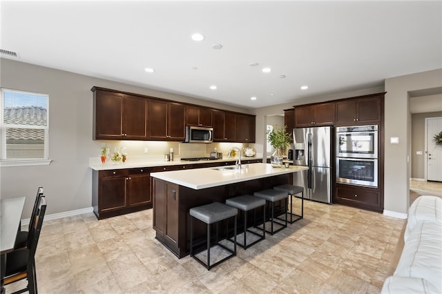 kitchen featuring sink, a breakfast bar area, dark brown cabinets, a center island with sink, and stainless steel appliances