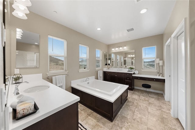 bathroom with vanity, plenty of natural light, and a tub to relax in