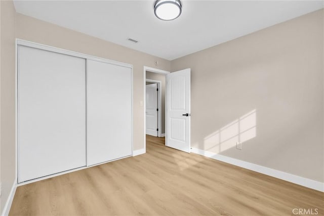 unfurnished bedroom featuring light hardwood / wood-style flooring and a closet