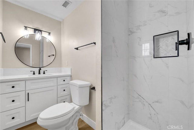 bathroom with vanity, wood-type flooring, a tile shower, and toilet