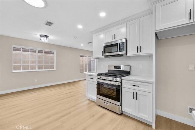 kitchen with white cabinetry, stainless steel appliances, and light hardwood / wood-style floors