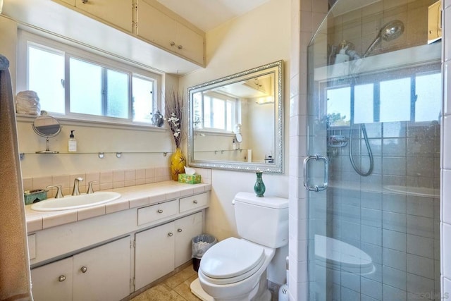 bathroom with vanity, toilet, and a shower with door