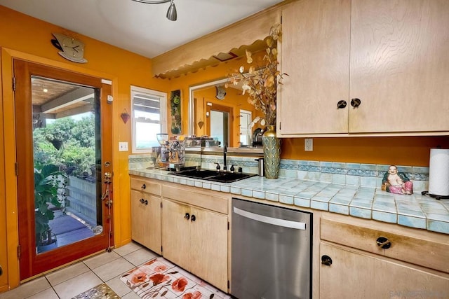 kitchen with sink, tile counters, dishwasher, and light tile patterned flooring