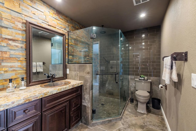 bathroom featuring vanity, toilet, a shower with shower door, and tile walls