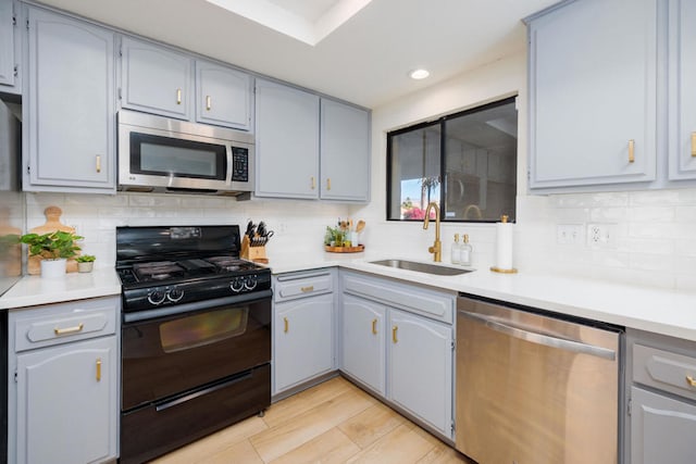 kitchen featuring gray cabinetry, sink, backsplash, and appliances with stainless steel finishes