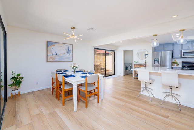 dining area with separate washer and dryer and light wood-type flooring