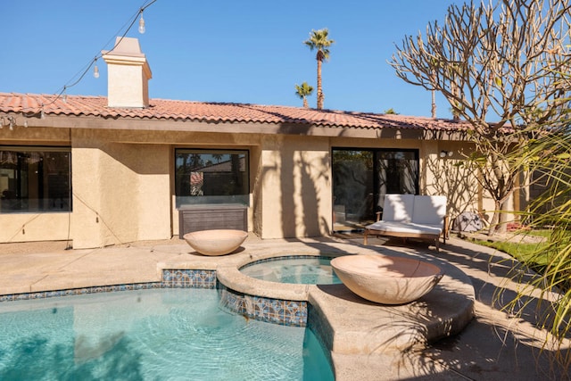 back of property featuring a swimming pool with hot tub and a patio area