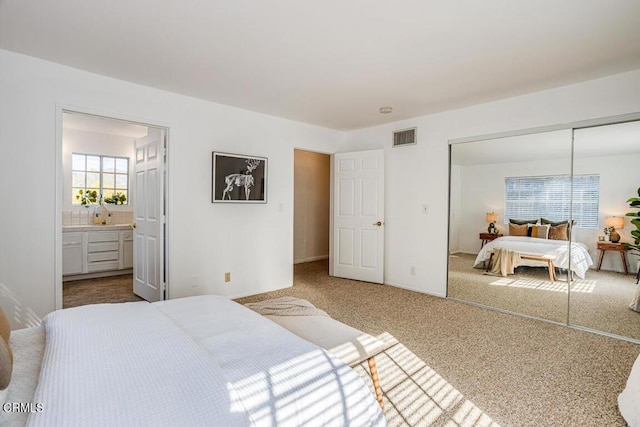 bedroom featuring a closet, connected bathroom, and carpet