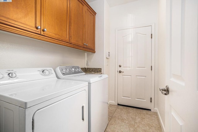 laundry area with light tile patterned flooring, cabinets, and washer and clothes dryer