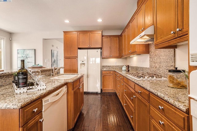 kitchen featuring dark hardwood / wood-style floors, sink, decorative backsplash, light stone countertops, and white appliances