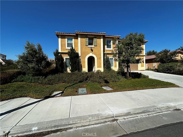 mediterranean / spanish-style house with a garage, a tile roof, driveway, and stucco siding