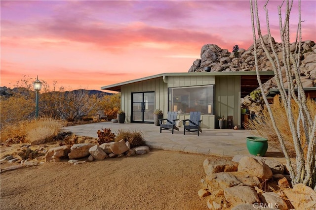 back house at dusk featuring a patio