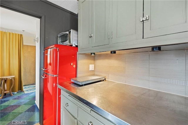 kitchen featuring backsplash, stainless steel counters, and refrigerator