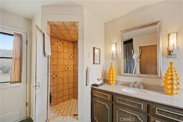 bathroom with tiled shower and vanity