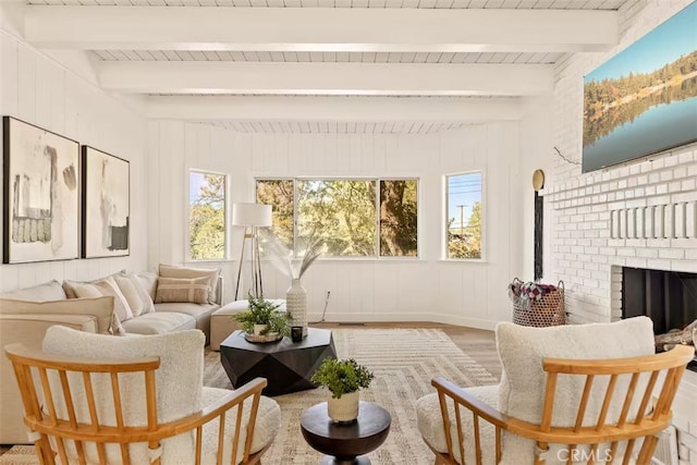 sunroom featuring beam ceiling and a brick fireplace