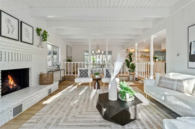 living room with hardwood / wood-style flooring, wood ceiling, a brick fireplace, and beamed ceiling