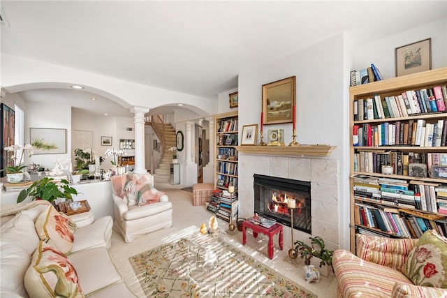 carpeted living room with ornate columns, a tiled fireplace, and built in shelves