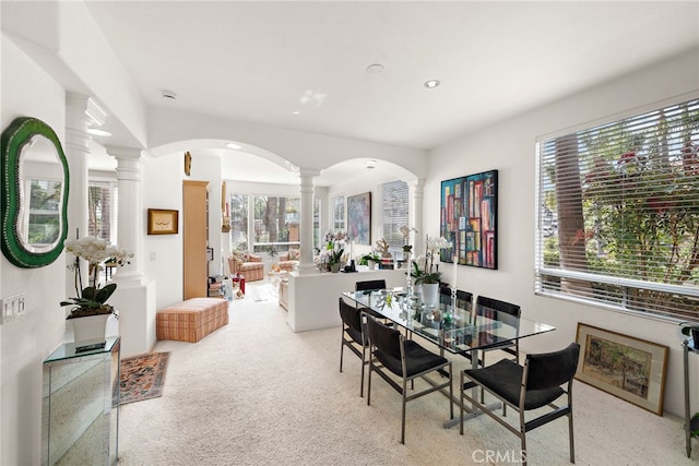 carpeted dining space with plenty of natural light and ornate columns