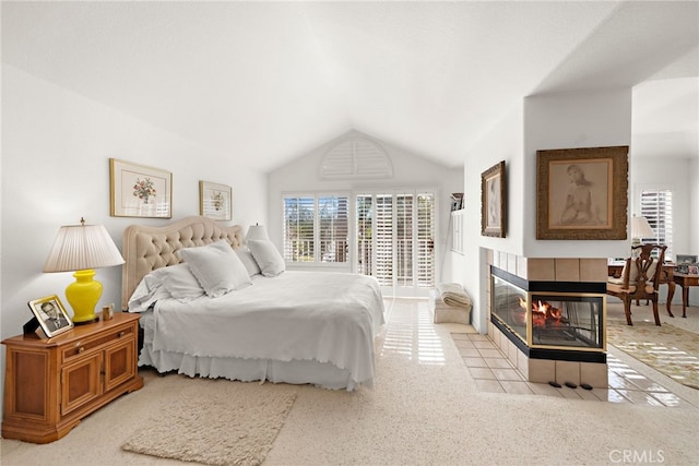 carpeted bedroom with a tile fireplace and lofted ceiling