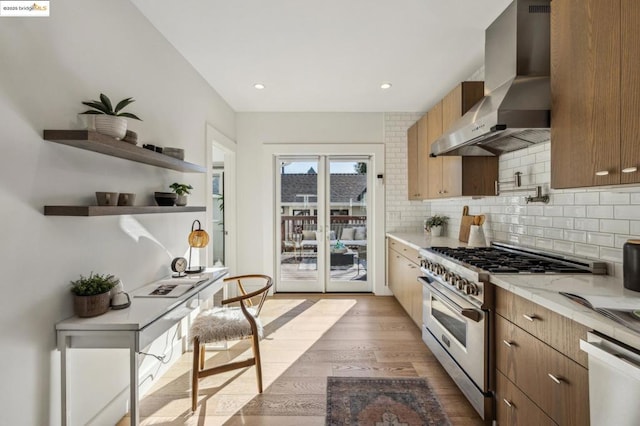 kitchen with tasteful backsplash, stainless steel range, light hardwood / wood-style floors, and wall chimney exhaust hood