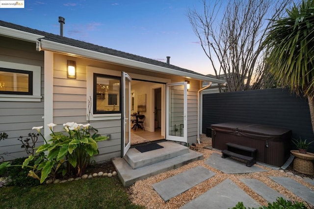 exterior entry at dusk featuring a hot tub