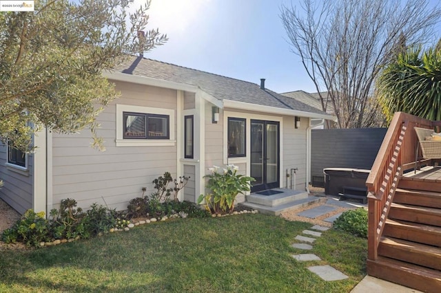 exterior space with a wooden deck, a hot tub, and a lawn