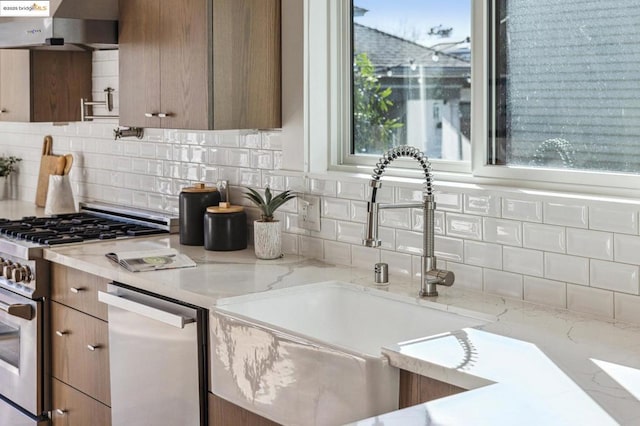 kitchen with light stone countertops, appliances with stainless steel finishes, sink, and backsplash