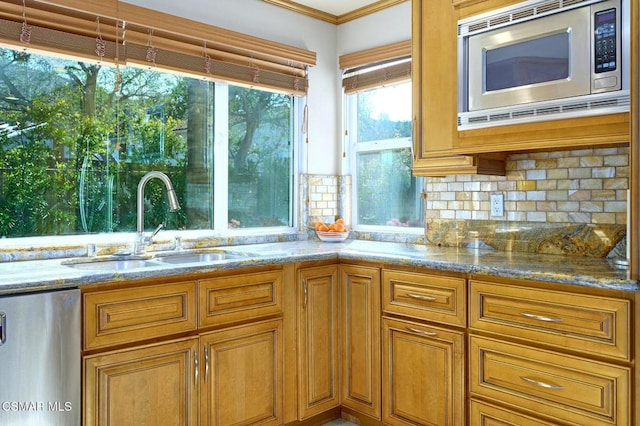 kitchen with sink, stainless steel microwave, dishwasher, light stone countertops, and decorative backsplash