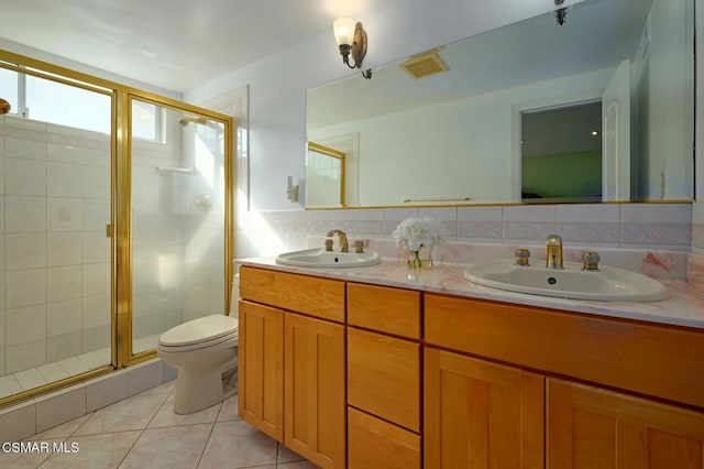 bathroom featuring tile patterned flooring, vanity, decorative backsplash, a shower with shower door, and toilet