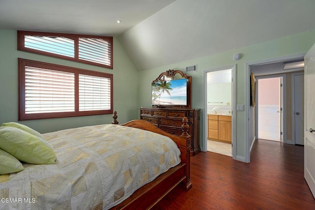 bedroom with lofted ceiling, dark hardwood / wood-style floors, and ensuite bath