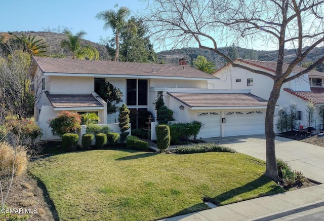 view of front facade featuring a garage, a mountain view, and a front lawn