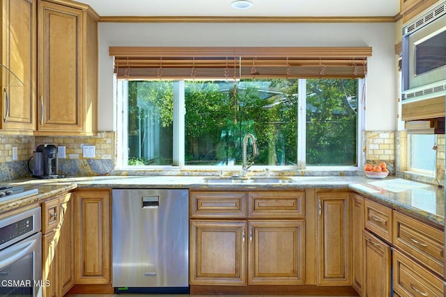 kitchen with appliances with stainless steel finishes, light stone countertops, sink, and decorative backsplash