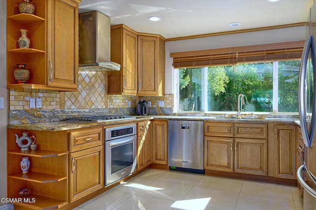 kitchen with sink, backsplash, stainless steel appliances, light stone countertops, and wall chimney exhaust hood