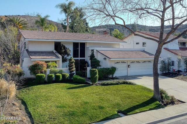 view of front facade with a garage, a mountain view, and a front yard