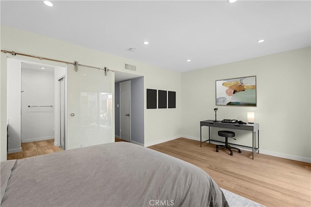 bedroom featuring a barn door and light wood-type flooring