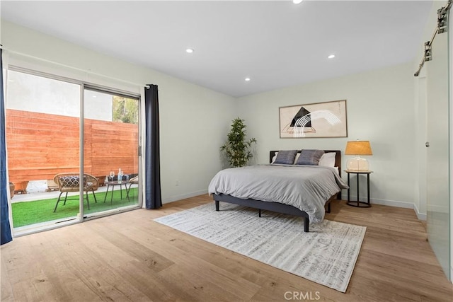 bedroom featuring a barn door, access to outside, and light hardwood / wood-style flooring