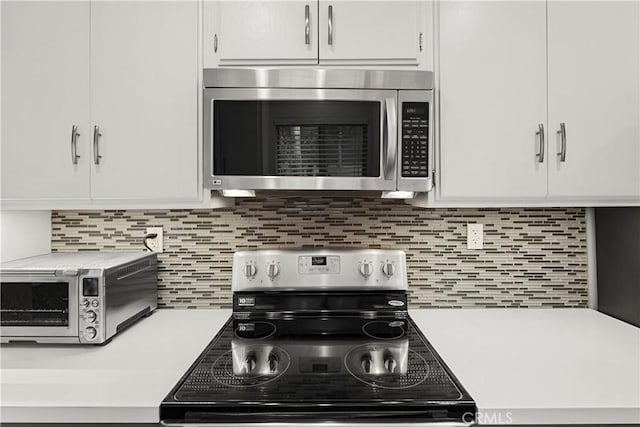 kitchen featuring white cabinetry, backsplash, and range with electric stovetop