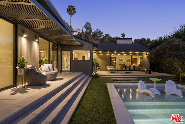 back house at dusk with a patio area