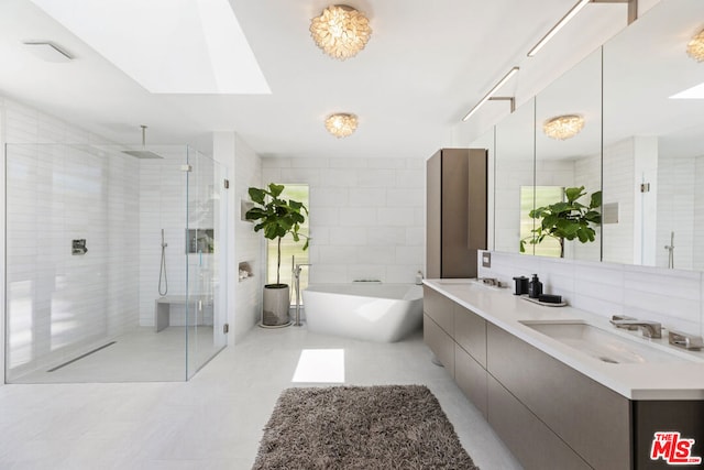 bathroom featuring plus walk in shower, tile walls, vanity, and a skylight