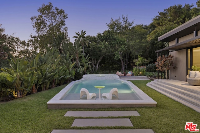 pool at dusk featuring a yard