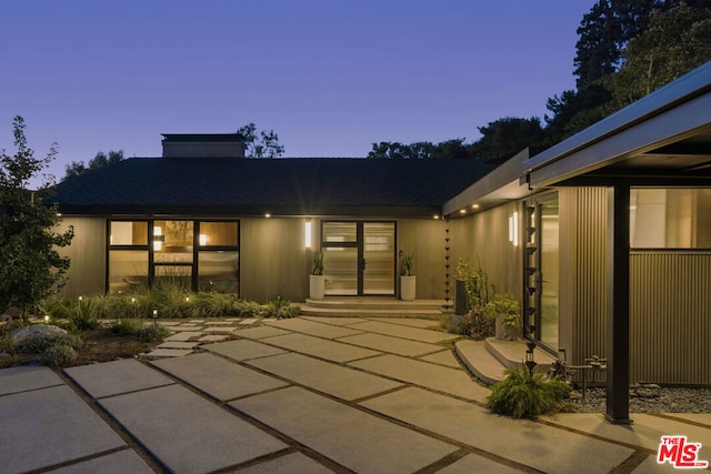 back house at dusk with a patio area