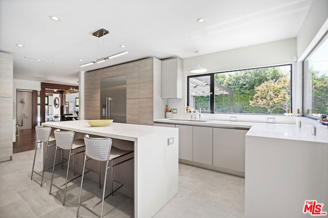 kitchen featuring pendant lighting, white cabinetry, sink, a breakfast bar area, and a center island