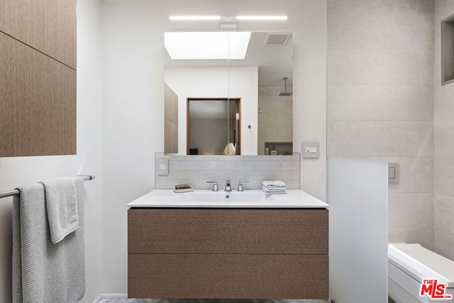 bathroom with a skylight, vanity, and decorative backsplash