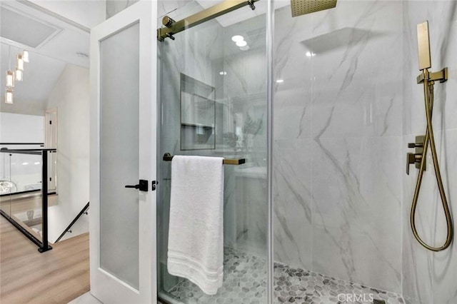 full bath with a marble finish shower and wood finished floors