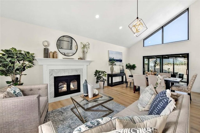 living room with light wood-style floors, a tile fireplace, high vaulted ceiling, and recessed lighting