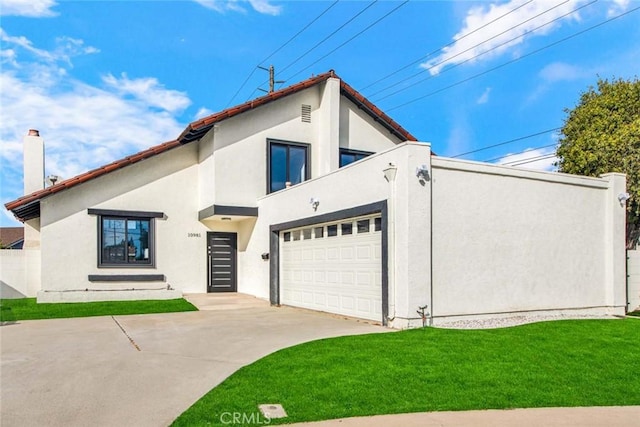 view of front of property with an attached garage, driveway, a front lawn, and stucco siding