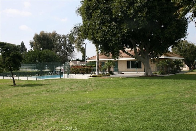 view of home's community with a yard, a pool, a patio area, and fence