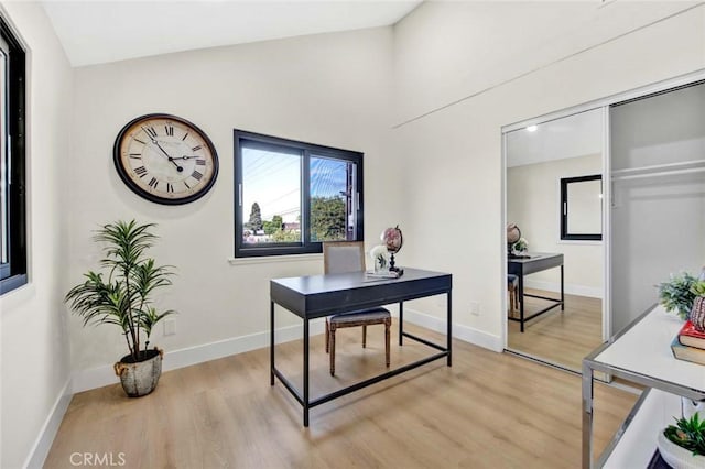 home office with lofted ceiling, light wood-type flooring, and baseboards