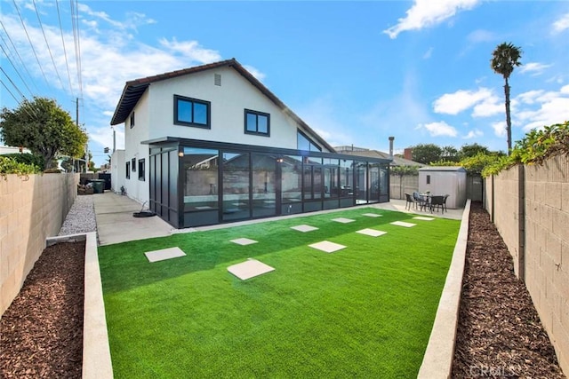 rear view of house featuring a sunroom, a fenced backyard, a patio, and stucco siding